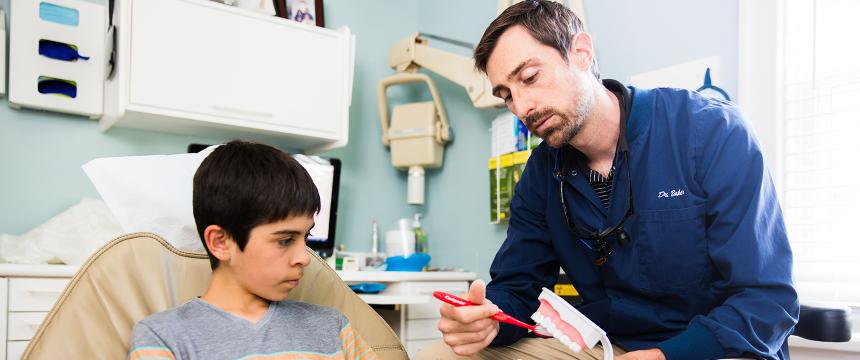 Dentist and young male patient talking about proper dental care.